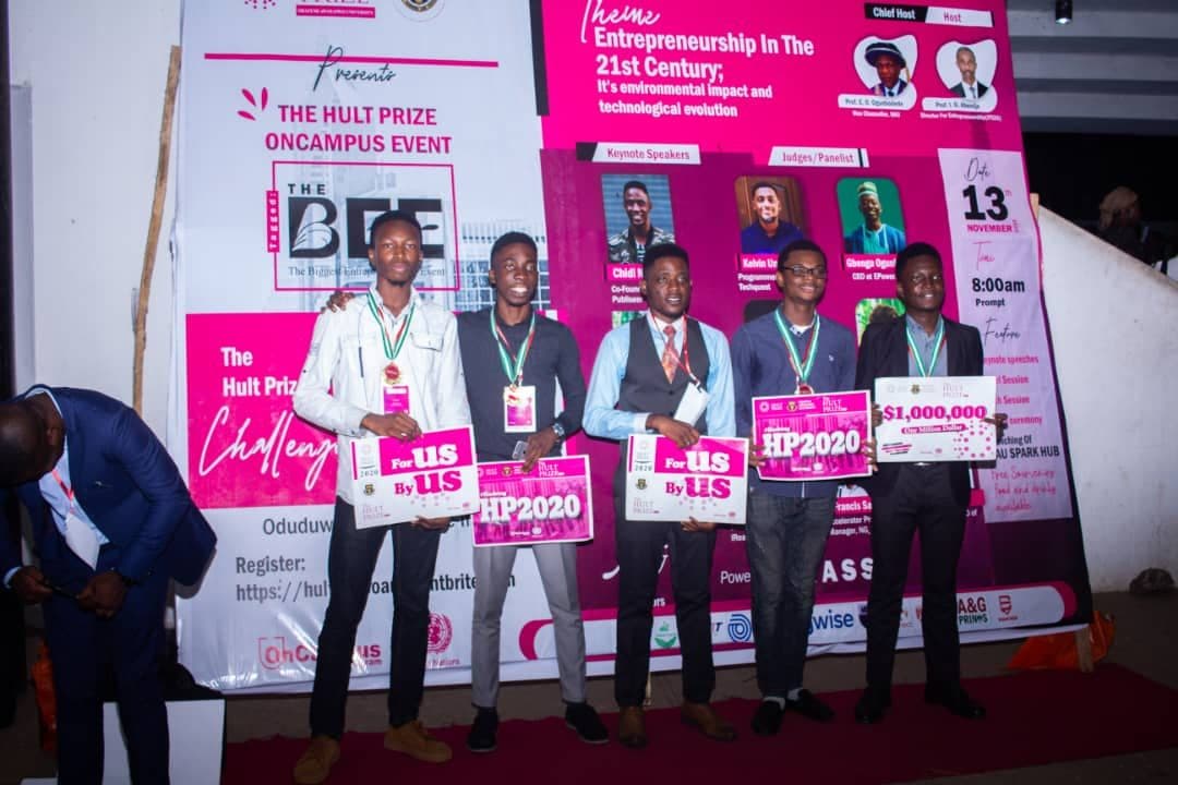 Students holding Hult Prize signs on stage at an on-campus event